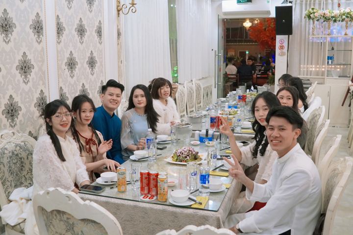 Bàn tiệc tất niên, mọi người ngồi ăn và trò chuyện