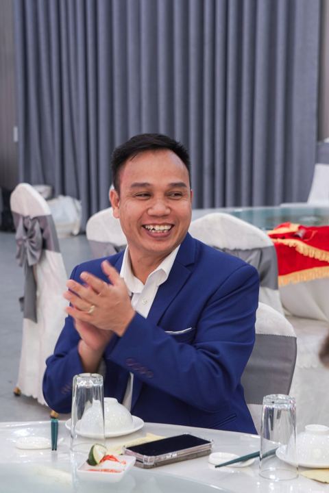 Anh quản lý cười vỗ tay tại bàn tiệc