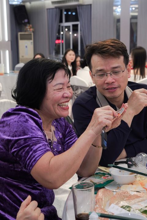Hai người vui vẻ bóc lì xì tại bàn tiệc